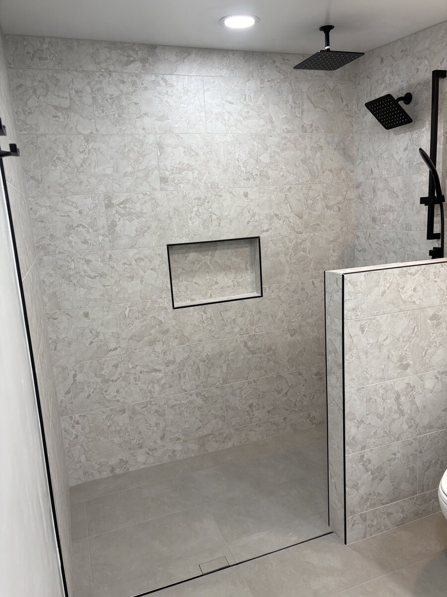 Bathroom renovation featuring recessed niche and tile walls